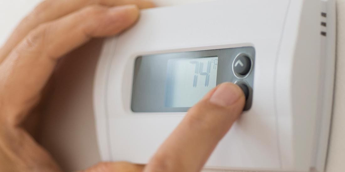 hand programming thermostat to lower your energy bill